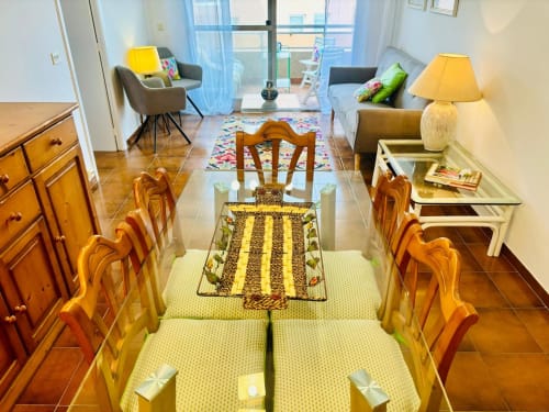 Comedor con sillas y mesa de madera en apartamento de Baiona con vistas al mar, moderno espacio habitable visible