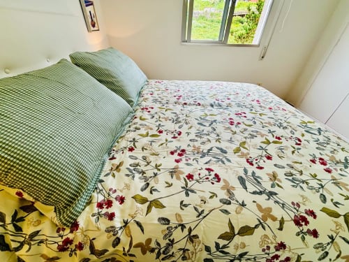 Luminoso dormitorio en apartamento Holibai de Baiona con ropa de cama de flores y vistas al mar por la ventana