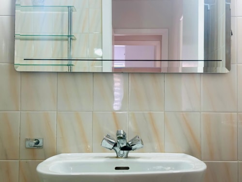 Lavabo moderno con grifo cromado y espejo en apartamento de Baiona con vistas al mar