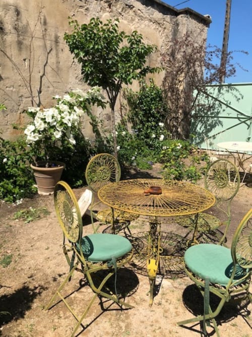 Yellow bistro table and chairs in Domaine de l'Ocrerie's garden courtyard, Pourrain