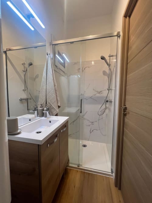 Salle de bains moderne avec double vasque, paroi de douche vitrée et carrelage imitation marbre au Camping La Lézardière