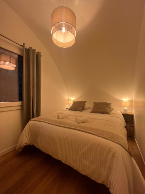 Chambre moderne du Camping La Lézardière avec luminaires suspendus, lit double et ambiance chaleureuse