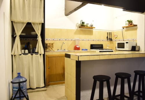 Cocina moderna amarilla con taburetes negros en Hotel LLUNA, Oaxaca