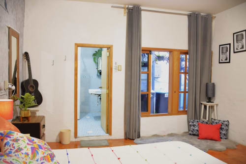 Colorida habitación del departamento LLUNA en Oaxaca con vistas al jardín, guitarra acústica y mobiliario moderno