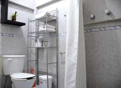 Baño moderno del hotel LLUNA en Oaxaca con azulejos grises, cabina de ducha de vidrio y accesorios blancos