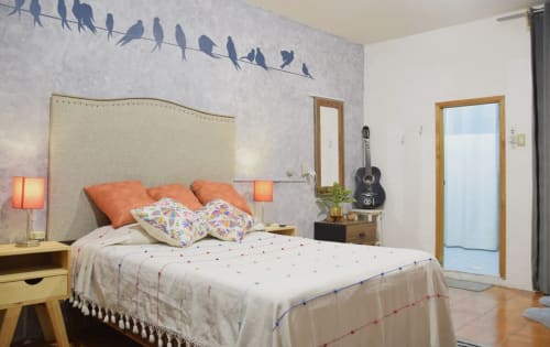 Acogedor dormitorio en el apartamento LLUNA de Oaxaca con arte de pájaros, detalles naranjas, guitarra y vistas al jardín