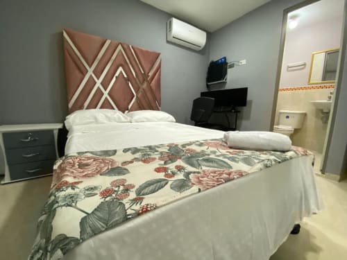 Habitación moderna del hotel Casa Mango en Cali con cama queen, cabecero geométrico y baño privado