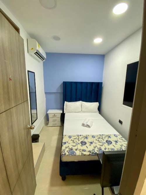 Habitación moderna en Casa Mango, Cali: cama queen, pared azul, aire acondicionado y mobiliario minimalista
