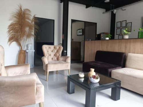 Moderno salón de recepción del hotel Casa Mango en Cali con muebles color crema, mesa de café negra y plantas decorativas