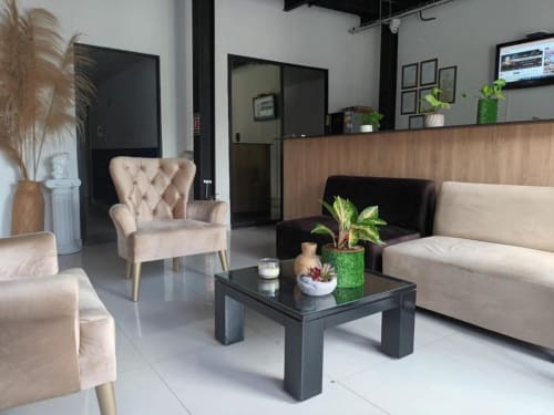 Moderno lobby del hotel CASA MANGO en Cali con asientos beige, mesa de café negra y plantas en macetas