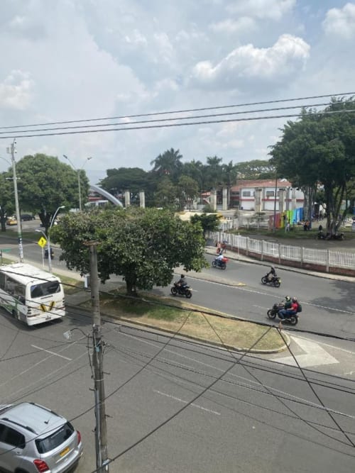 Vista callejera del hotel Casa Mango en Cali, Colombia con motocicletas, calle arbolada y arquitectura local