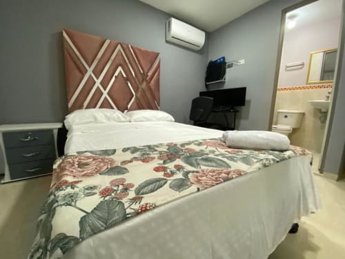 Habitación del hotel Casa Mango en Cali con cama queen, cabecero geométrico, ropa de cama floral y baño privado