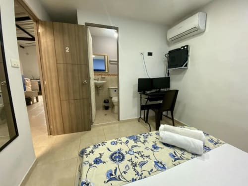 Habitación del hotel Casa Mango en Cali con cama, escritorio de trabajo, TV, aire acondicionado y baño privado