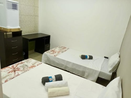 Camas gemelas con toallas en el hotel Casa Mango de Cali, Colombia, con escritorio y aire acondicionado