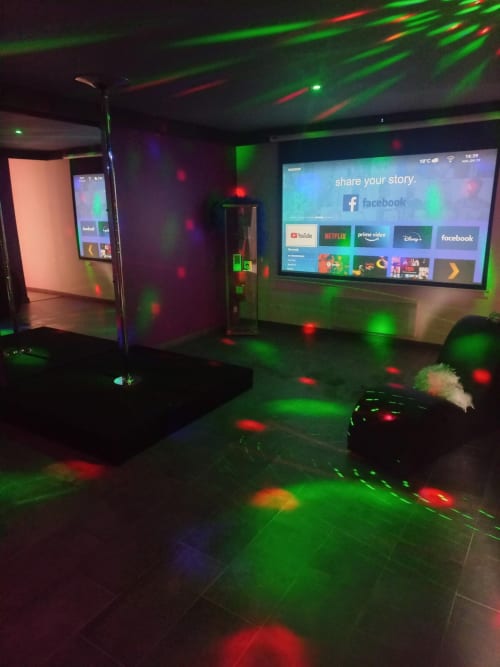 Salle de karaoké moderne à la villa La Maison du Plaisir avec lasers verts et rouges, grand écran TV et équipement interactif