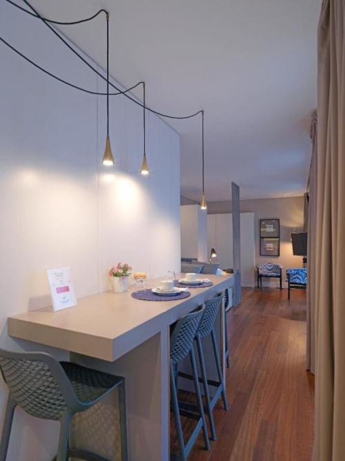 Modern studio apartment dining area in Porto with kitchen island, pendant lights, wooden floors, and contemporary furnishings