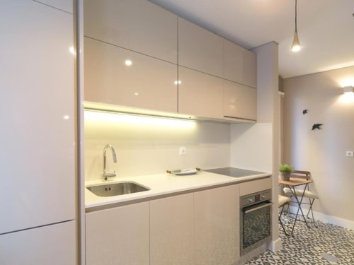Modern kitchen in New Oporto Apartments studio, Porto, with cream cabinetry, stainless steel sink, induction cooktop, and