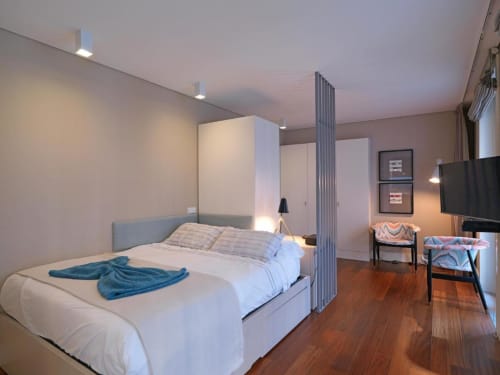 Modern studio bedroom at New Oporto Apartments in Porto with queen bed, partition wall, wooden floors, and living area with