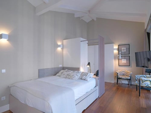 Modern hotel suite at New Oporto Apartments in Porto with canopy bed, wood floors, and contemporary furnishings