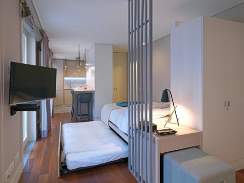 Studio apartment at New Oporto Apartments in Porto with twin beds, TV, kitchenette, and city view through modern room