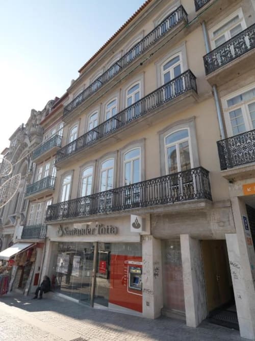Historic Haussmann-style building in Porto housing New Oporto Apartments with wrought-iron balconies and ground-floor shops