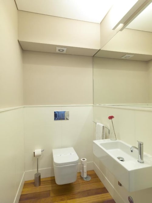 Modern bathroom in New Oporto Apartments Porto with white fixtures, wooden floor, and cream tile walls