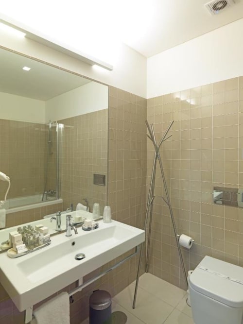 Modern bathroom at New Oporto Apartments in Porto with white sink, tiled walls, shower enclosure, and toilet