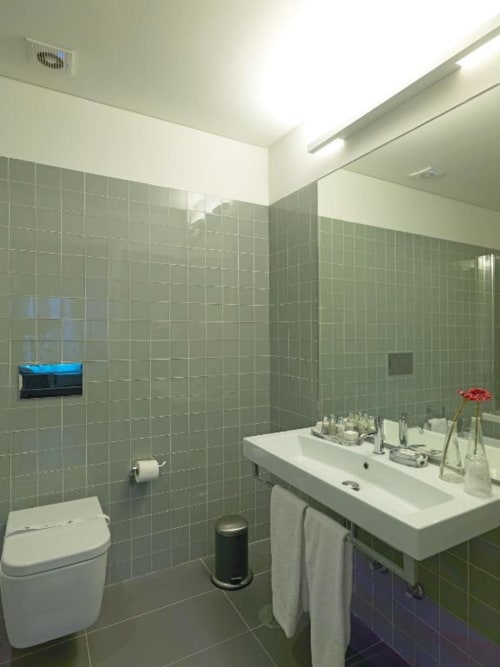 Modern bathroom at New Oporto Apartments in Porto with green tile walls, white sink, toilet, and shower enclosure