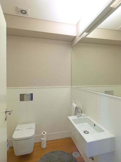 Modern bathroom in Superior Apartment at New Oporto Apartments Porto with white toilet, sink, mirror, and wooden flooring