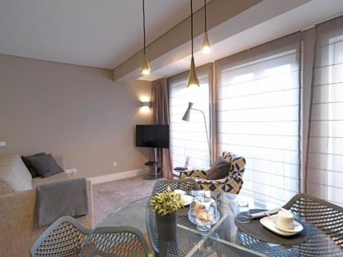 Deluxe apartment dining area at New Oporto in Porto with city views, modern pendant lights, and comfortable seating