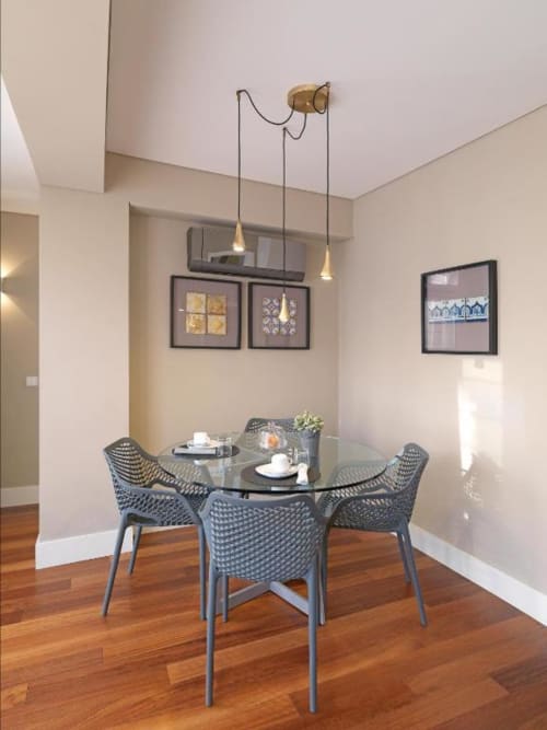 Modern dining area in New Oporto Apartments Porto with round glass table, gray patterned chairs, pendant lights, and wall