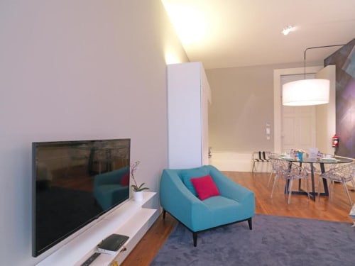 Modern living area in Superior Apartment at New Oporto Apartments, Porto, with turquoise sofa, flat-screen TV, dining table,