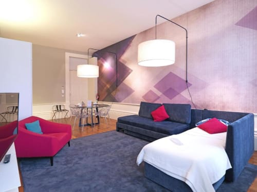 Deluxe apartment at New Oporto Apartments featuring modern living room with red armchair, navy sofa bed, dining area, and