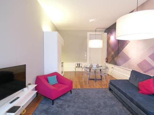 Modern deluxe apartment living area at New Oporto Apartments, Porto, with pink accent chair, sofa bed, dining table, and
