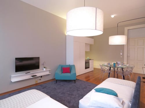 Superior Apartment at New Oporto Apartments in Porto featuring bedroom, living area with turquoise armchair, dining table,