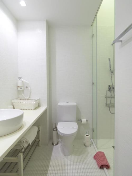Modern bathroom in Deluxe Apartment at New Oporto Apartments Porto, featuring toilet, sink, shower enclosure, and white tile