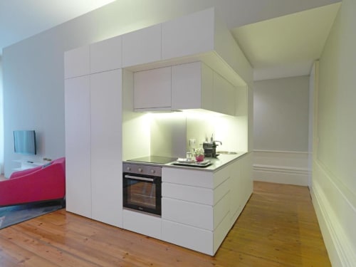 Modern white kitchenette in Porto apartment with wooden floors, built-in oven, and ambient lighting