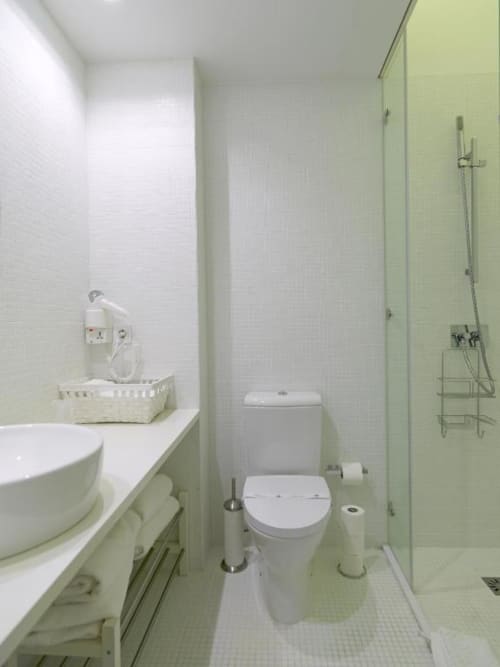 Modern bathroom in New Oporto Apartments, Porto with white tile walls, toilet, sink vanity, and shower enclosure