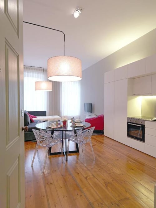 Deluxe Apartment dining area at New Oporto Apartments in Porto, with round table, crystal chairs, and modern pendant lights