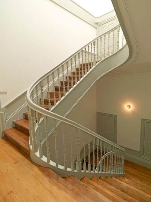 Elegant curved staircase with white railings and wooden steps in New Oporto Apartments Porto, featuring modern architectural
