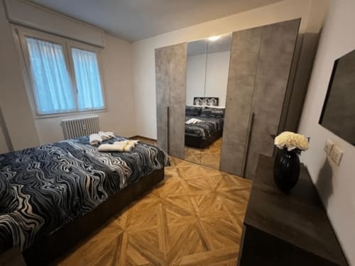 Modernes Schlafzimmer im EmilBo' House mit Spiegelschrank, gemusterter Bettwäsche, Holzböden und Fenster in San Lazzaro di Savena