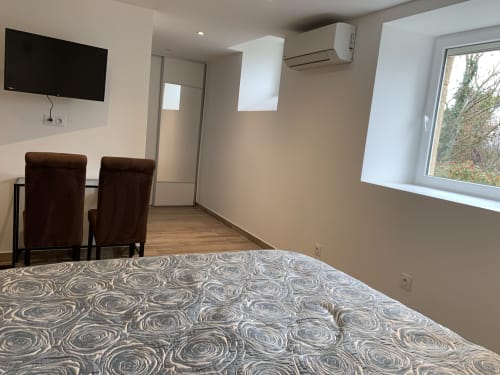 Chambre moderne du Restaurant du Port avec literie à motifs, fauteuils marron, télévision, climatisation et vue sur le jardin à Saint
