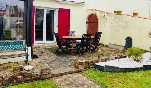 Patio cosy du gîte avec table à manger, sièges et jardins paysagers à Conciergerie Pour Tous, Darazac