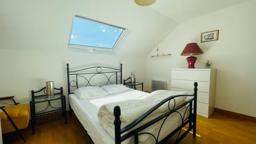 Chambre mansardée lumineuse avec velux, lit en métal noir, commode blanche et parquet chez Conciergerie Pour Tous By Patty