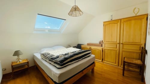 Chambre mansardée lumineuse avec velux, meubles en bois et vue sur le jardin du gîte Conciergerie Pour Tous à Darazac