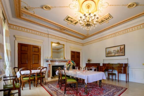 Elegant formal dining room at Domaine de Bize Mirepoix with chandeliers, fireplace, and period furniture