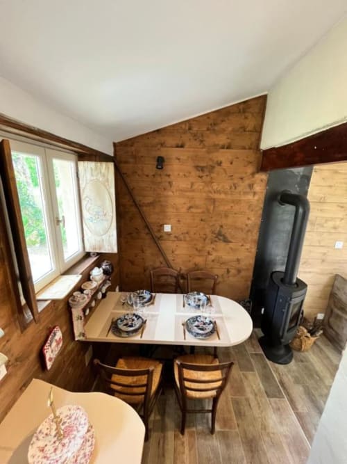 Salle à manger cosy de Les papillons de baccara à Gondrin avec table en bois, vue sur jardin et poêle de masse