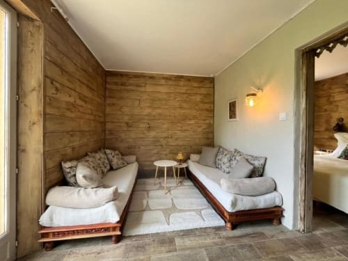 Salon cosy du Les papillons de baccara avec murs en bois, deux lits de repos et vue sur le jardin à Gondrin