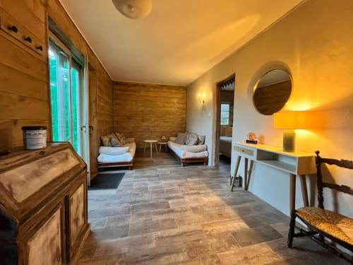 Intérieur cosy du cottage Les papillons de baccara à Gondrin avec murs en bois, sièges confortables et vue sur le jardin