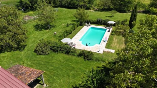 Vue aérienne de la piscine turquoise des Papillons de Baccara entourée de jardins luxuriants à Gondrin, France